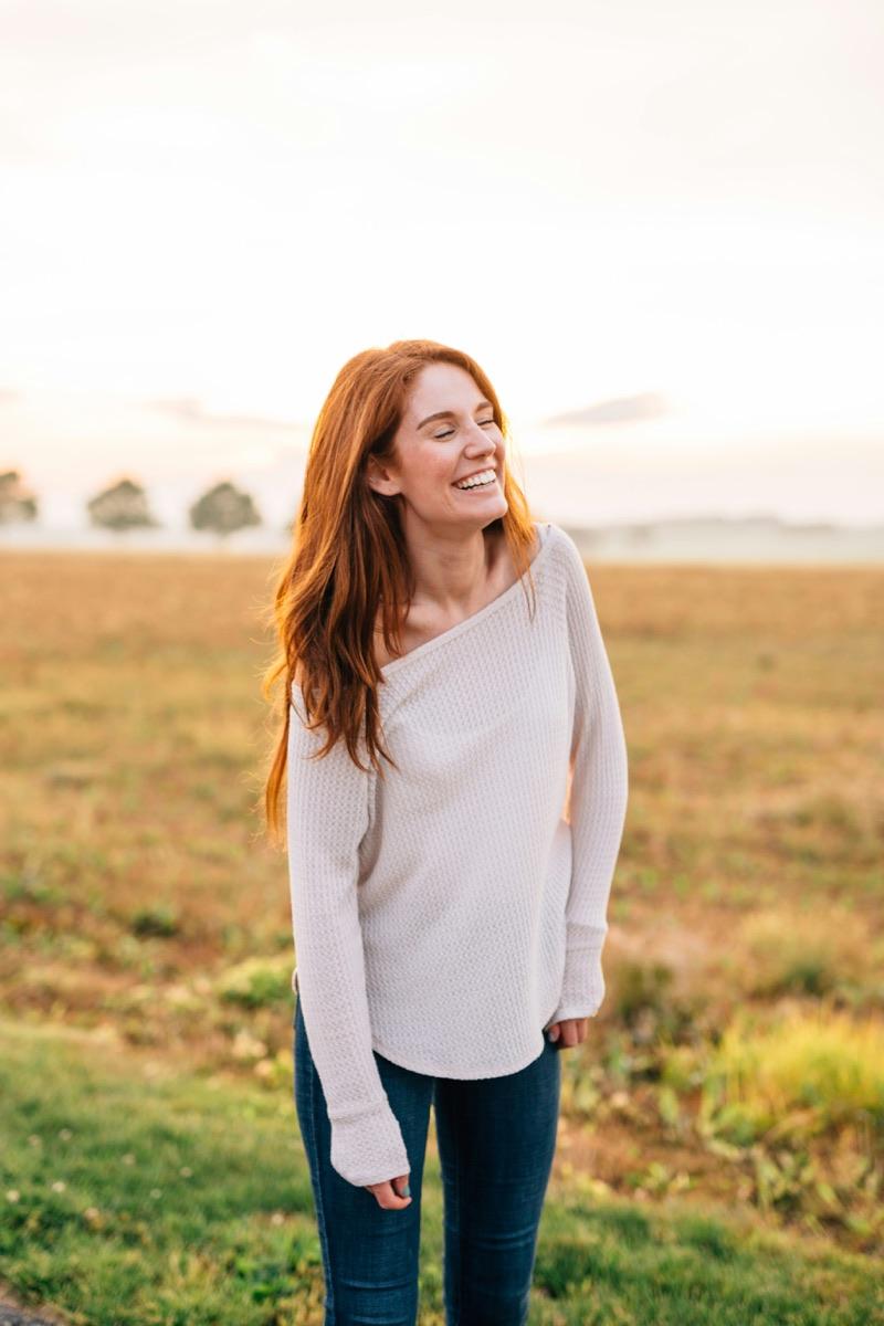Smiling consumer standing in a field at sunrise