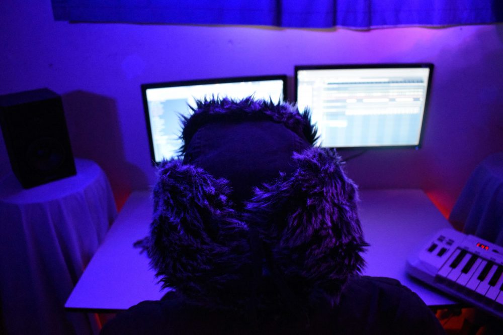 a person with a hat looking at two screens