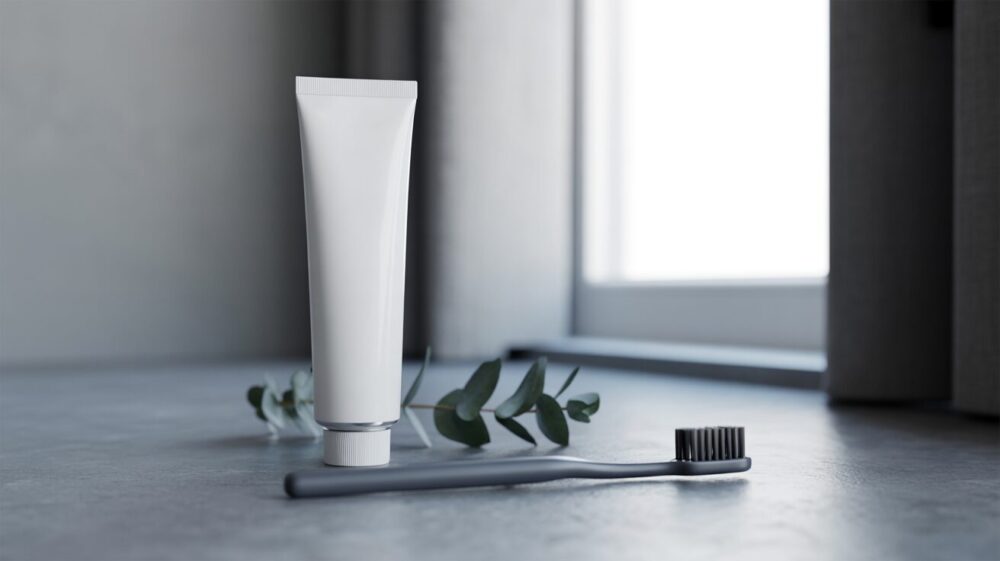 toothpaste and a toothbrush on a countertop next to a leaf.