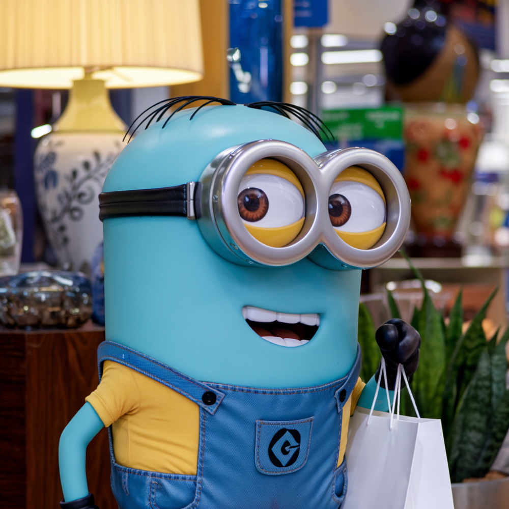 A blue minion with a shopping bag, smiling.